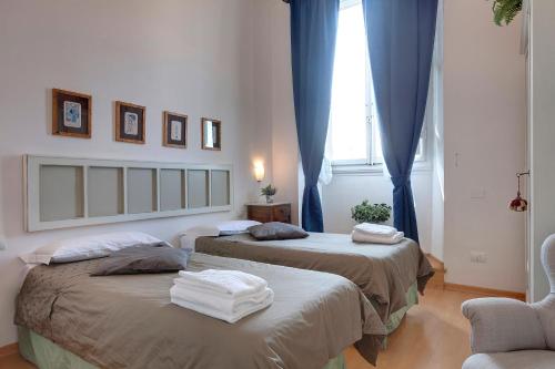2 camas en una habitación con cortinas azules y ventana en Cappelle Medici, en Florencia