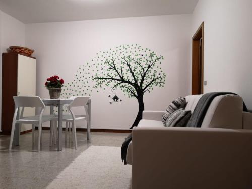 a living room with a table and a tree on the wall at CASETTA DI FEM in Sabbionara