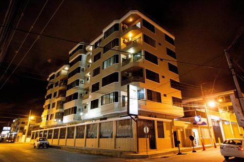 a tall building at night with cars parked in front of it at Hotel Bucaneiro in Manta