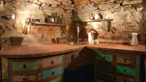 une cuisine avec un évier et un mur en pierre dans l'établissement Wild boar mountain, South of France very private and pool, à Bédarieux