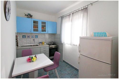 a kitchen with blue cabinets and a table and a refrigerator at Apartments Zoro in Primošten