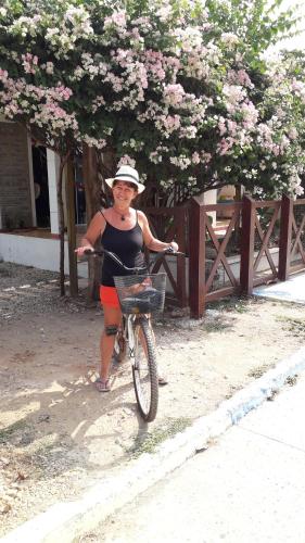 Una mujer está parada junto a una bicicleta. en Monkey Afro Hostel, en San Antero