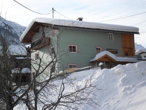 a house on a snow covered hill with a building at Ferienhaus Nadine in Kappl