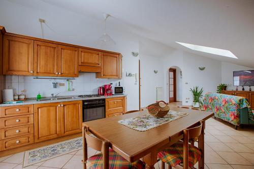 una cocina con armarios de madera y una mesa con sillas. en Casa Alpina - Aosta, en Aosta