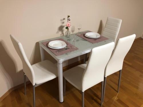 einem Esstisch mit weißen Stühlen und einem Tisch mit Tellern in der Unterkunft Corso Apartman in Kaposvár