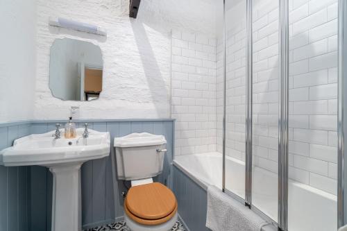 La salle de bains est pourvue de toilettes, d'un lavabo et d'une baignoire. dans l'établissement Rose Cottage, à Paignton