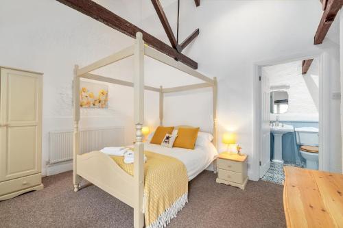a bedroom with a canopy bed and a bathroom at Rose Cottage in Paignton