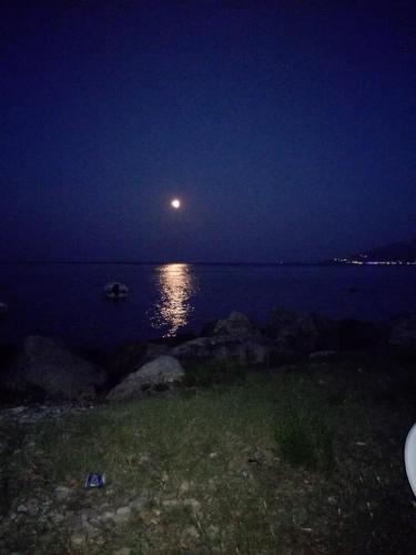 a moon over a body of water at night at Tony studio & apartments in Laganas