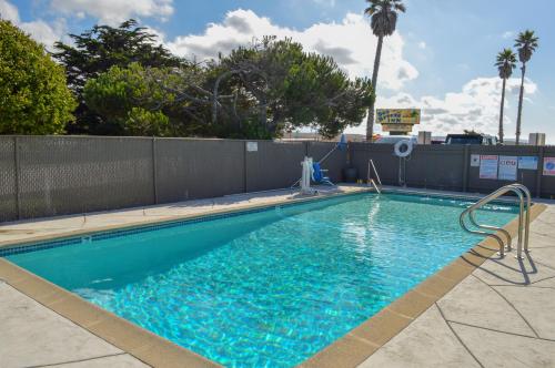 a swimming pool with blue water in front of a fence at Sea Breeze Inn - San Simeon in San Simeon