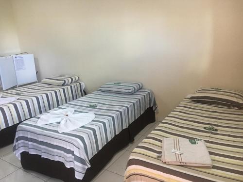 three beds are lined up in a room at Hotel Porto Real in Pôrto Real