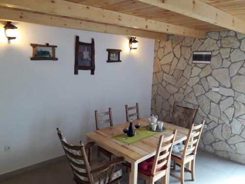 a wooden table with chairs and a stone wall at Pensions Airport in Podgorica