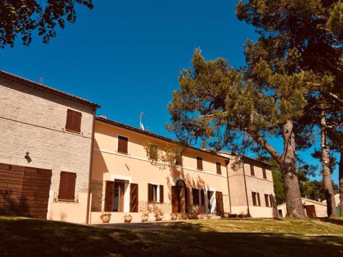 a large white building with a tree in the foreground at Villa Brettino- Pesaro mare e cultura - intera struttura con piscina in Fano
