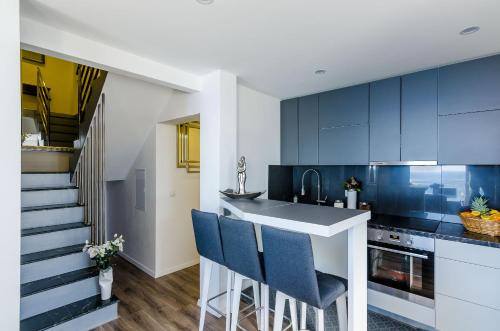 a kitchen with blue cabinets and a bar with blue chairs at Superior apartment Nike in Mlini