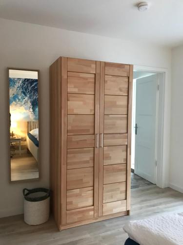 a wooden cabinet in a bedroom with a mirror at SEASIDE APARTMENTS - BEACHHOUSE BLUE in Eckernförde