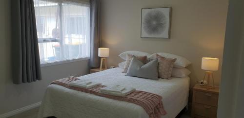 Rose Apartments Unit 6 Central Rotorua-Accommodation & Spa في روتوروا: غرفة نوم عليها سرير وفوط