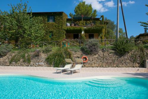 トルジャーノにあるAgriturismo La Montagnolaの背景に家があるプール(椅子2脚付)