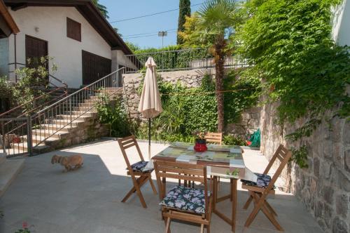 a patio with a table and an umbrella and a dog at Studio apartman Tasha in Opatija