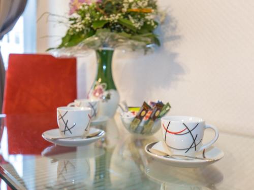 a glass table with two cups and a vase with flowers at Pension Marie Prenzlauer Berg in Berlin