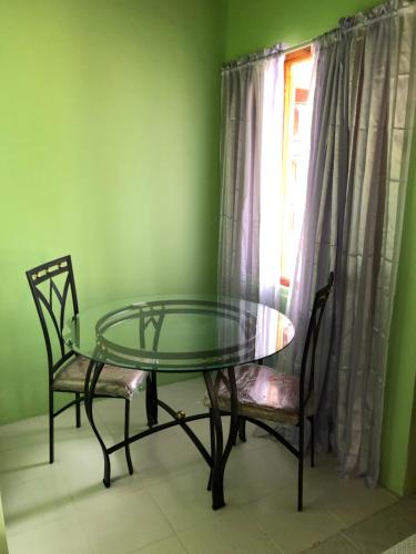 a glass table and two chairs in a room with a window at Seascape Apartments in Negril