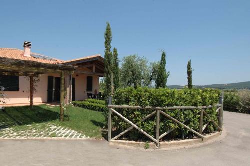 a house with a wooden gate in front of a yard at Casa in Maremma Tuscany Village in Scarlino