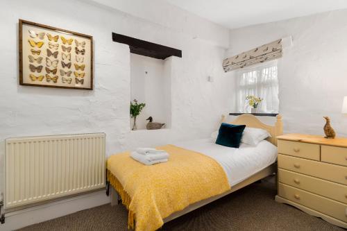 a bedroom with a bed with a yellow blanket at Jasmine Cottage in Paignton