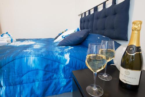 dos copas de vino en una mesa junto a una cama en Il grappolo -affittacamere- en Gavi