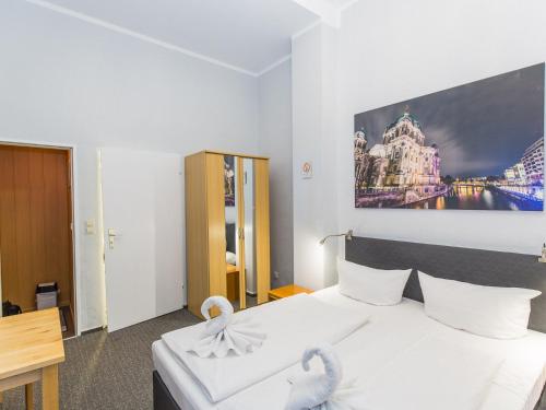 Un dormitorio con una cama blanca con una foto en la pared en Pension Marie Prenzlauer Berg, en Berlín