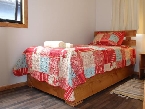 a bedroom with a bed with a red and white quilt at Aysén Cabañas in Puerto Aisén