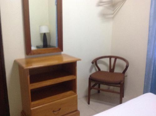 ein Schlafzimmer mit einer Kommode, einem Spiegel und einem Stuhl in der Unterkunft Mitchell's Guest House in DʼArbeau