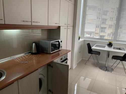 a kitchen with a microwave and a table with chairs at ARSS Apartment Skopje Main Square in Skopje