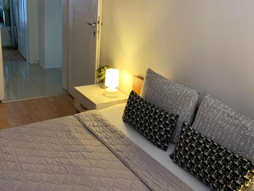 1 dormitorio con 1 cama con almohadas y lámpara en ARSS Apartment Skopje Main Square, en Skopje