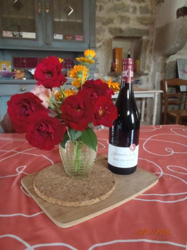 a bottle of wine and a vase of flowers on a table at La maison du Gué in Écutigny