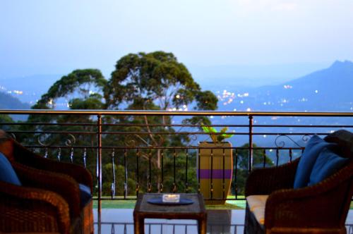 a balcony with two chairs and a table with a view at Rehoboth Mountain Suites in Mbabane