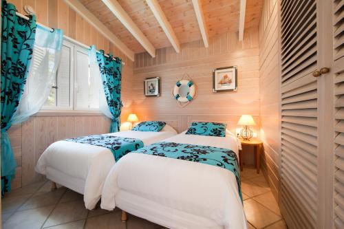 two beds in a room with wood paneling at Villa Le Lagon - Vision Luxe in Bonifacio