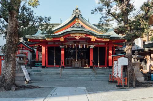 a temple with a red building with stairs and a tree at Juso AFP Apartment Hotel in Osaka
