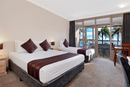 a hotel room with two beds and a balcony at Comfort Resort Waters Edge in Port Macquarie