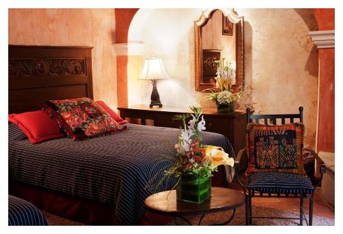 a bedroom with a bed and a table and a mirror at Meson de Maria in Antigua Guatemala