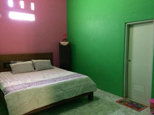 una camera da letto con pareti verdi e rosa e un letto di Fidigri Homestay a Cikembulan