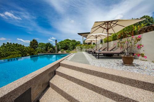 einen Pool mit Stühlen und einem Sonnenschirm neben einem Haus in der Unterkunft Ranis Lodge in Kampung Padang Masirat