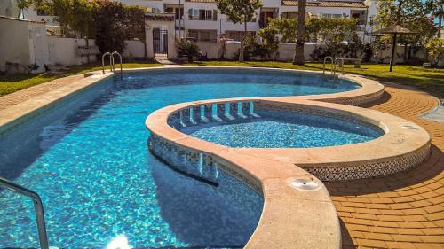 een zwembad met blauw water in een tuin bij La Casita Blanca - Vistabella Golf in Orihuela