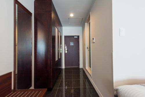 a room with a corridor with a bed and a door at Hotel Sonia Otaru in Otaru
