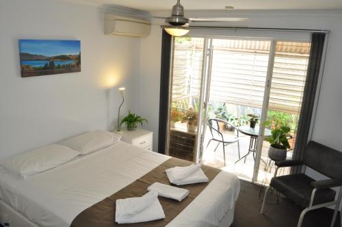 a bedroom with a large bed and a balcony at Isla House Greenslopes in Brisbane