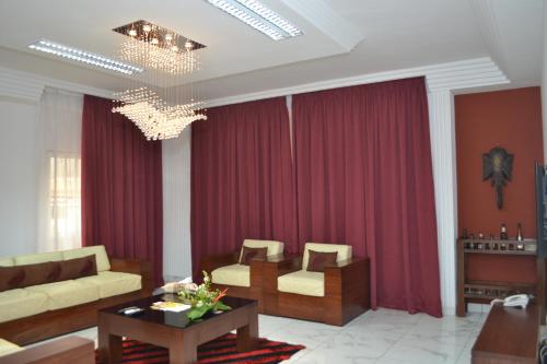 a living room with red curtains and a couch and a table at Residence Maryka II in Cotonou
