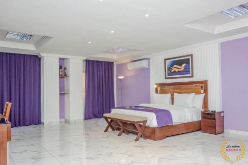 a bedroom with a large bed with purple curtains at Residence Maryka II in Cotonou