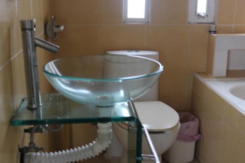 a bathroom with a glass sink and a toilet at Hotel Villas del Rey in Chachalacas