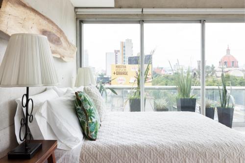 a bedroom with a bed and a large window at Departamento en Condesa con vista al Castillo de Chapultepec GYM - POOL - PARKING in Mexico City