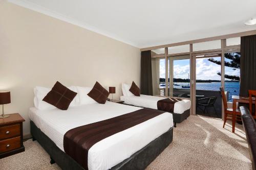two beds in a hotel room with a view of the water at Comfort Resort Waters Edge in Port Macquarie