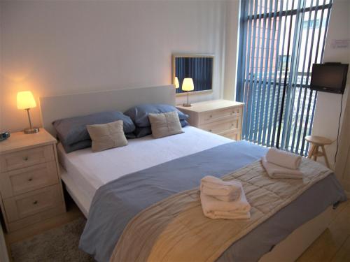 1 dormitorio con 1 cama grande y 2 toallas. en Stay Deansgate Apartments for 14 nights plus, en Mánchester