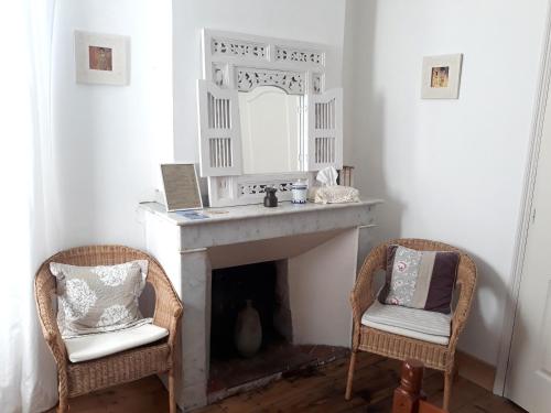 a living room with two chairs and a fireplace at Maison Rives - Village du Livre de Montolieu in Montolieu