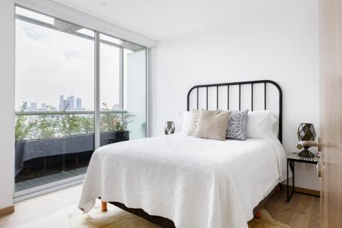 a bedroom with a white bed with a large window at Departamento en Polanco con Impresionante vista a la ciudad GYM - POOL - PARKING in Mexico City